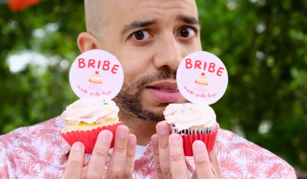 man holding cupcakes with bribe card